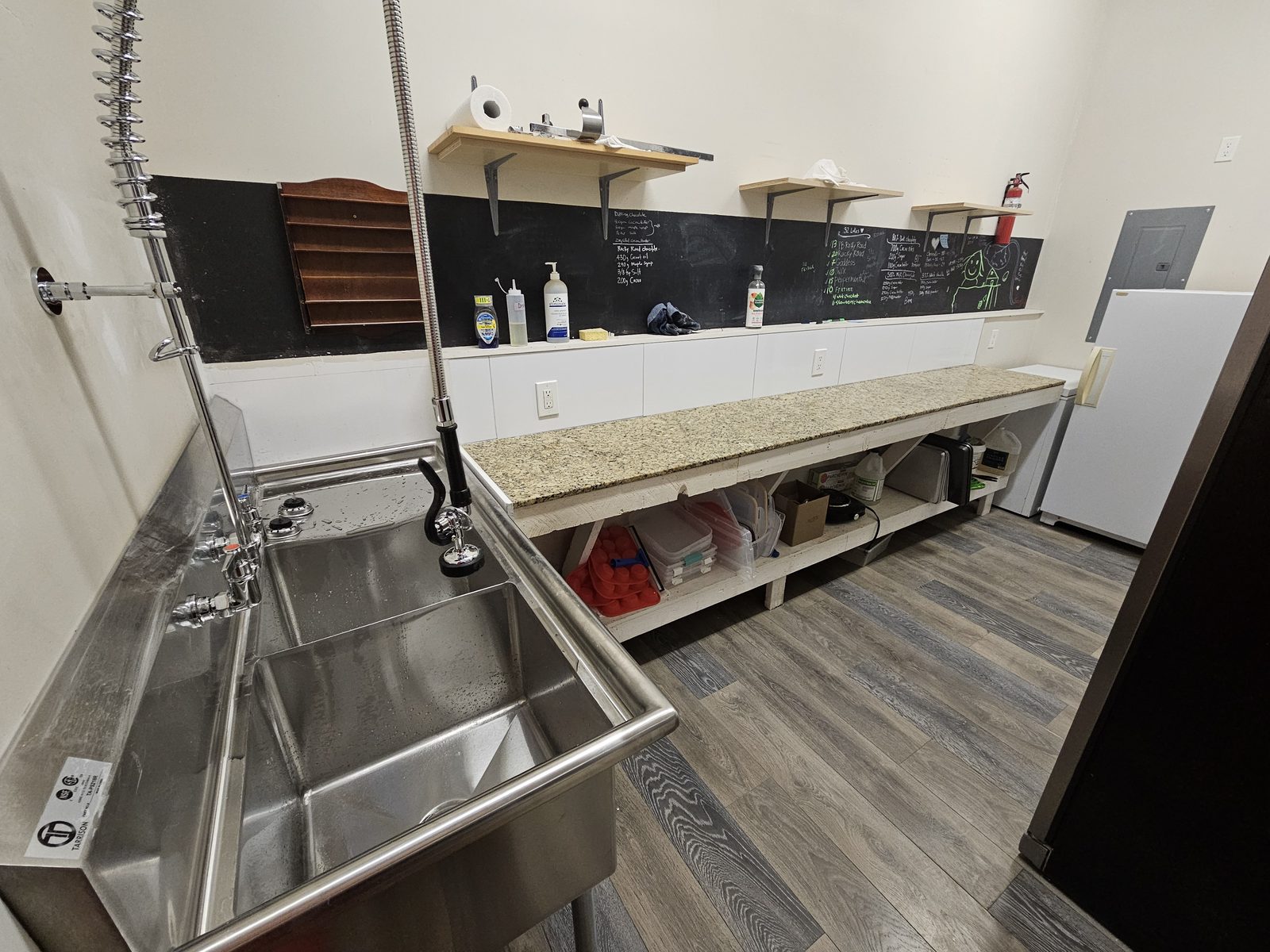 A commercial prep kitchen with a two-basin stainless sink and spray nozzle