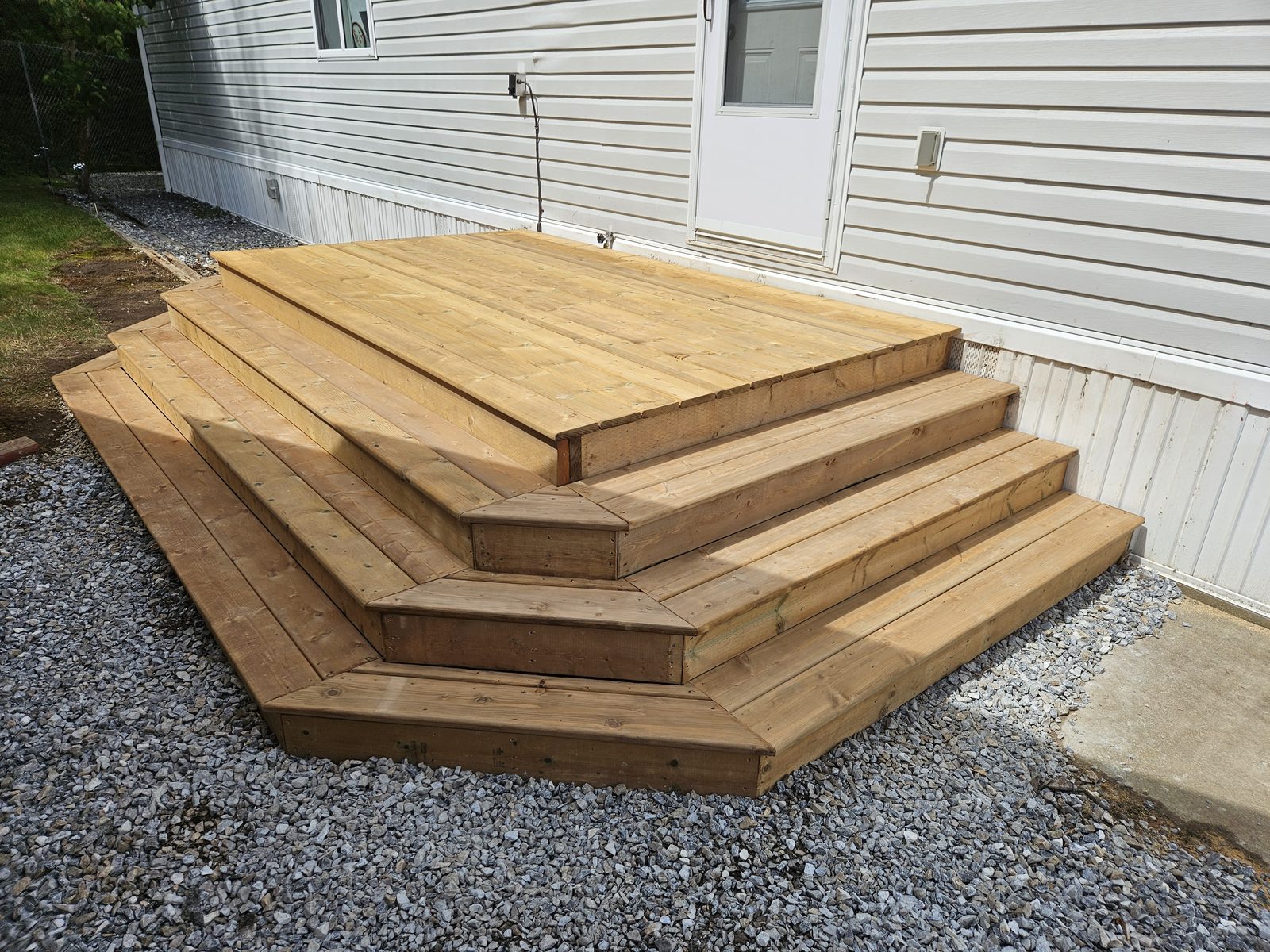 A freestanding pressure-treated deck with mitred wrap-around steps at a mobile home