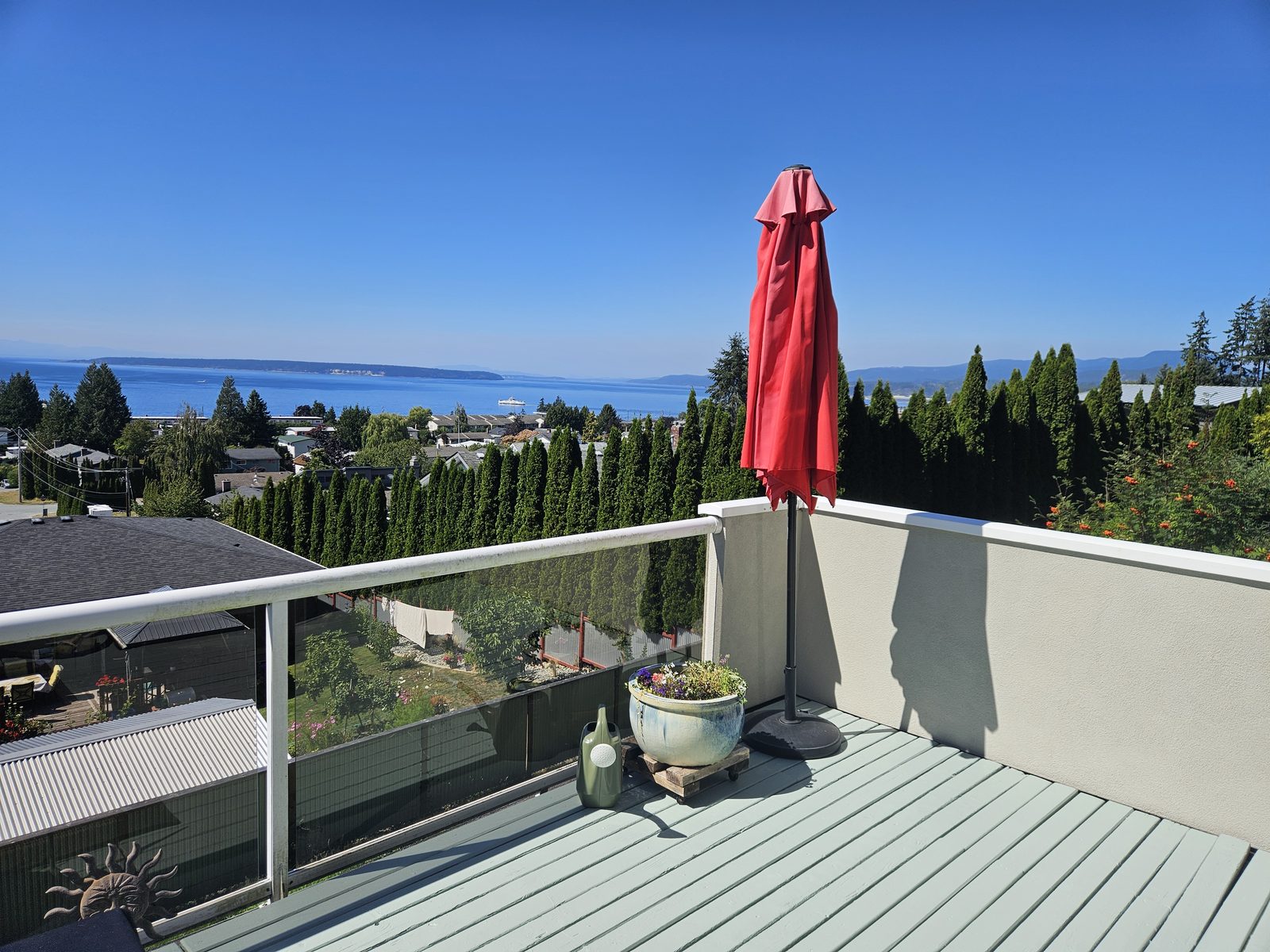 A deck refinished in a solid seafoam stain, overlooking the strait from Westview