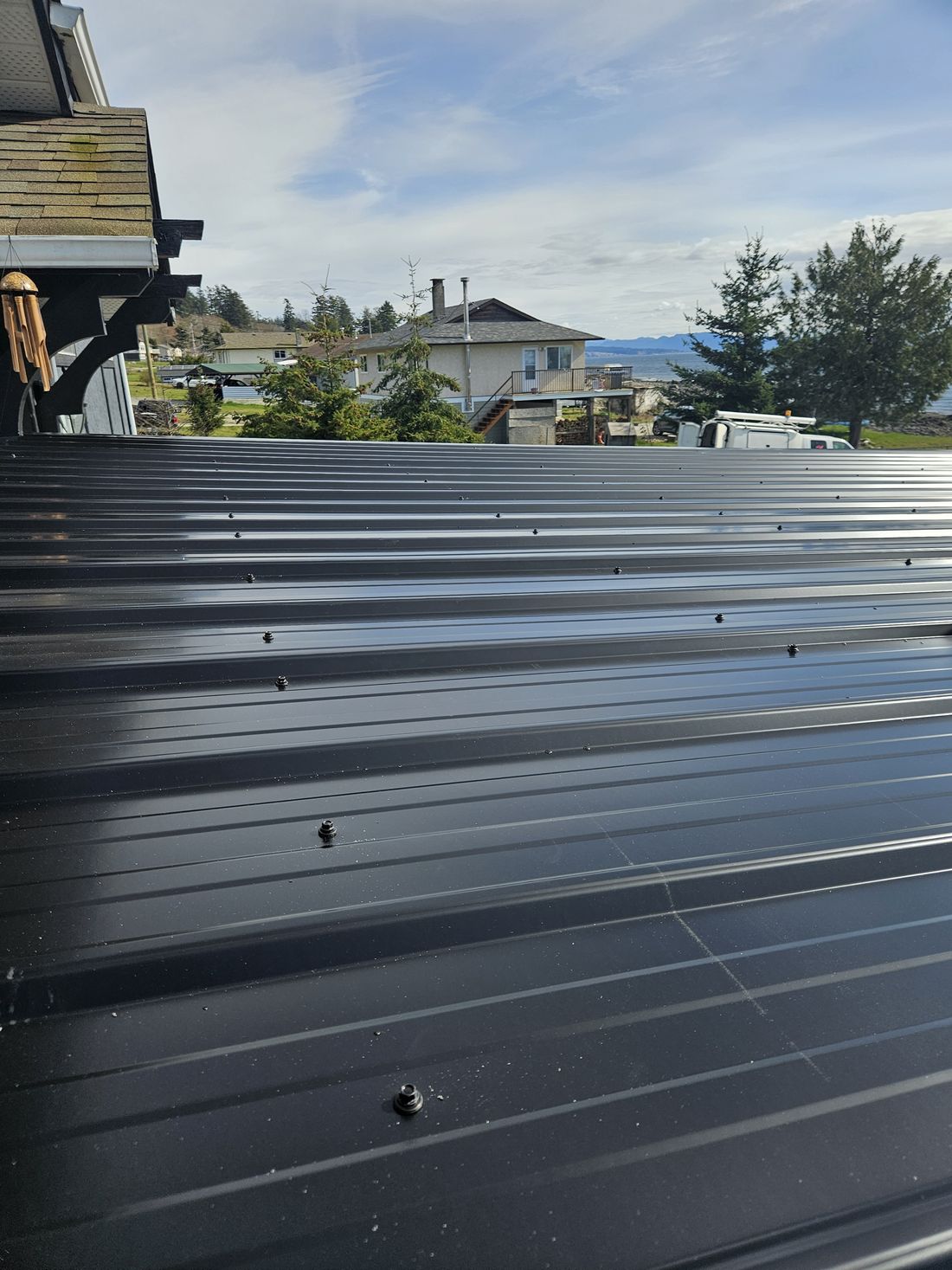 Black metal roofing on a post and beam deck cover above the water