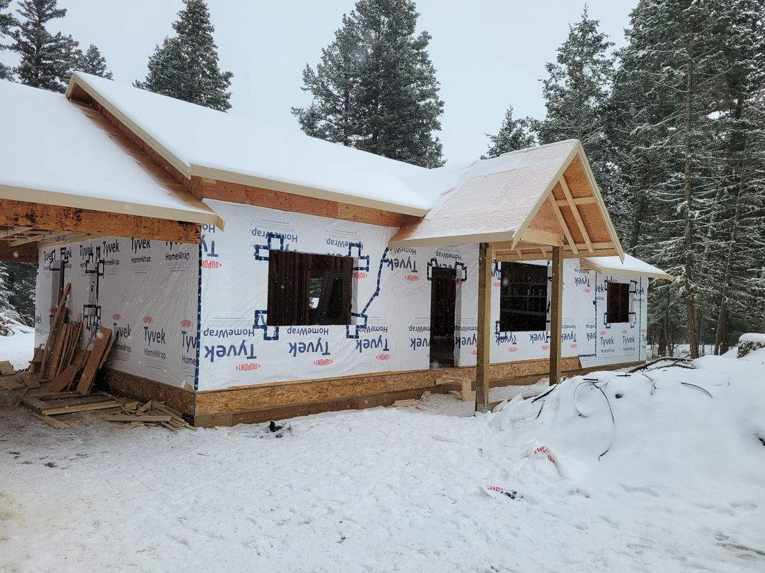 A rancher framed, wrapped and roofed in deep snow