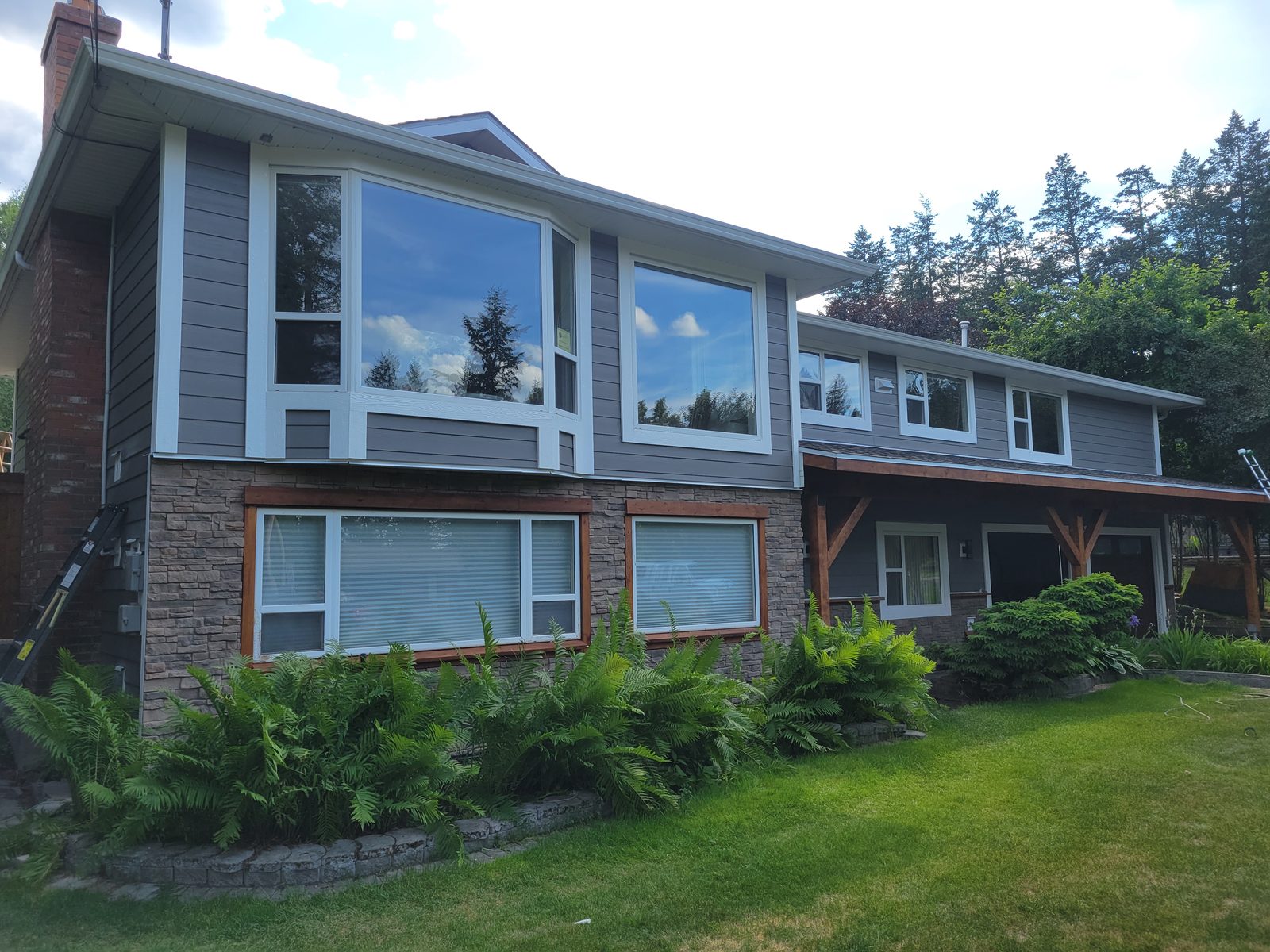 A Williams Lake home after a full exterior upgrade, with Hardie board siding, stone veneer and a new covered walkway