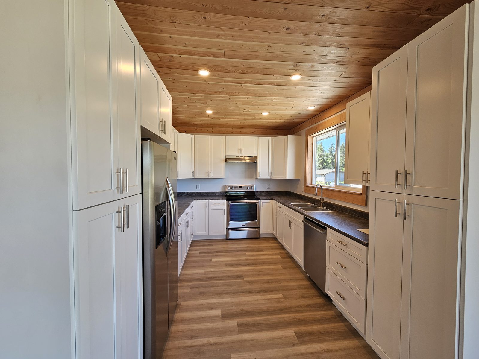 A renovated Westview kitchen with white cabinets and a fir tongue-and-groove ceiling