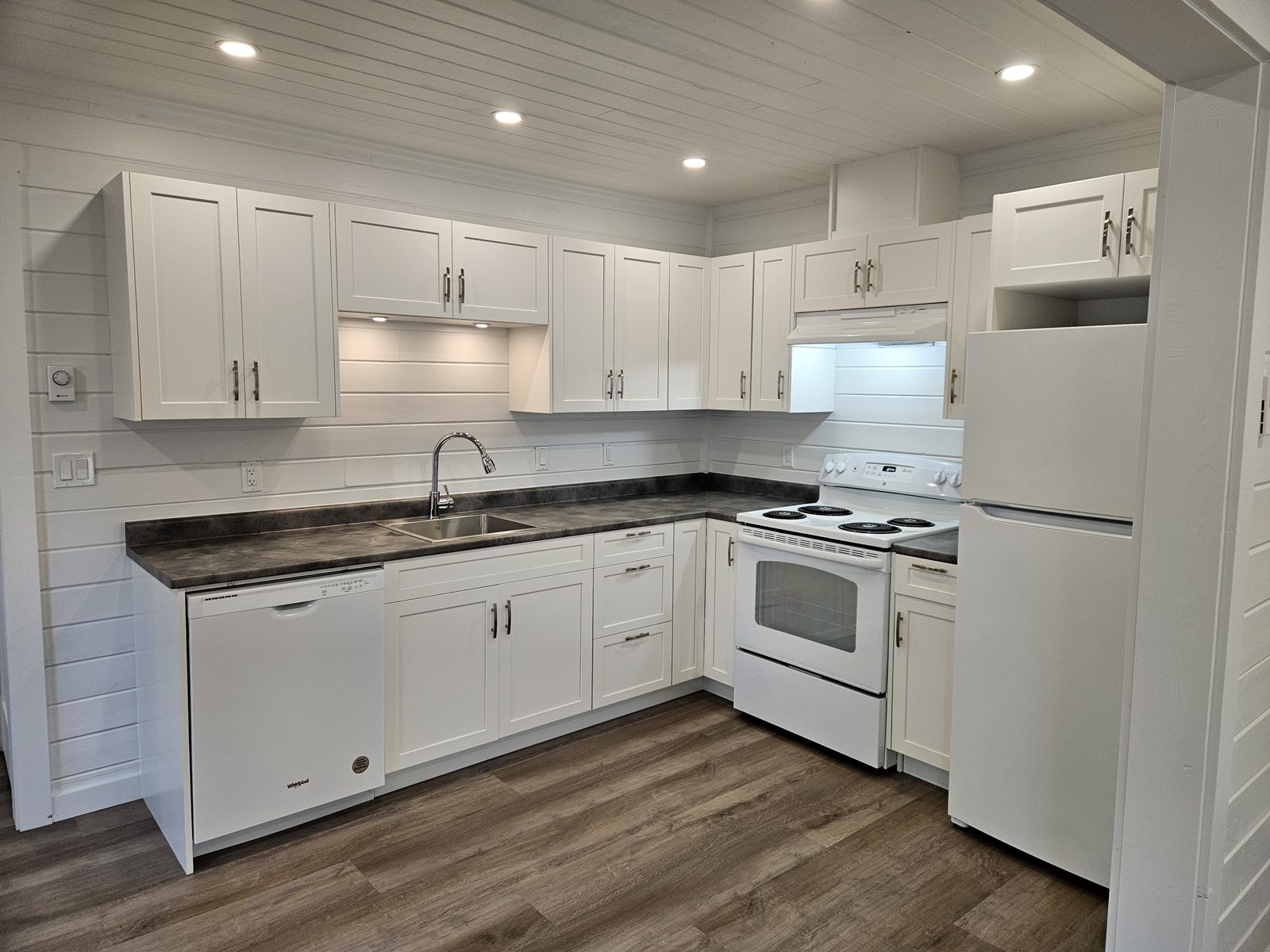 A rebuilt kitchen with white cabinets and tongue-and-groove walls in a 1930s house