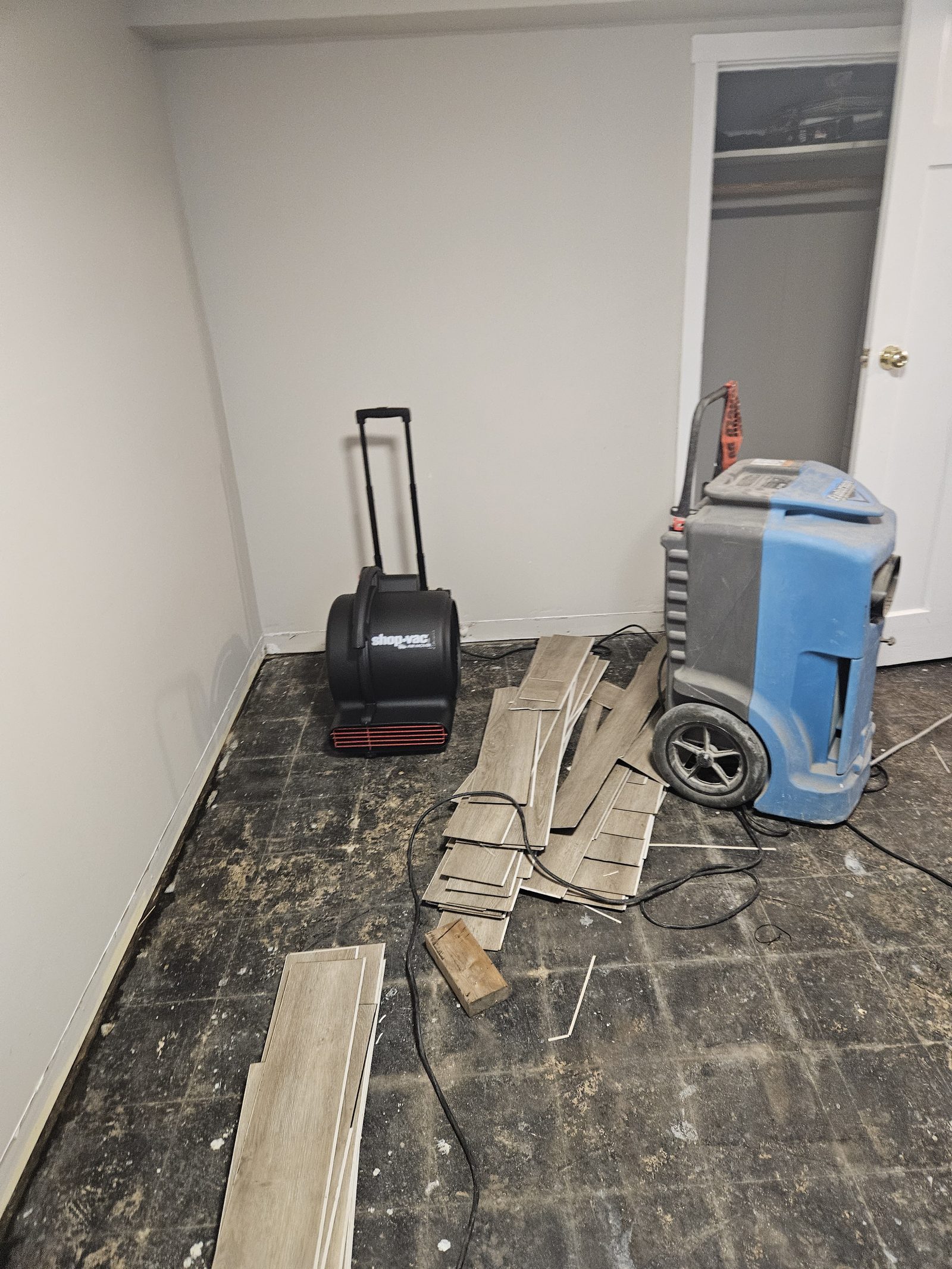 An air mover and dehumidifier running in a stripped room during drying